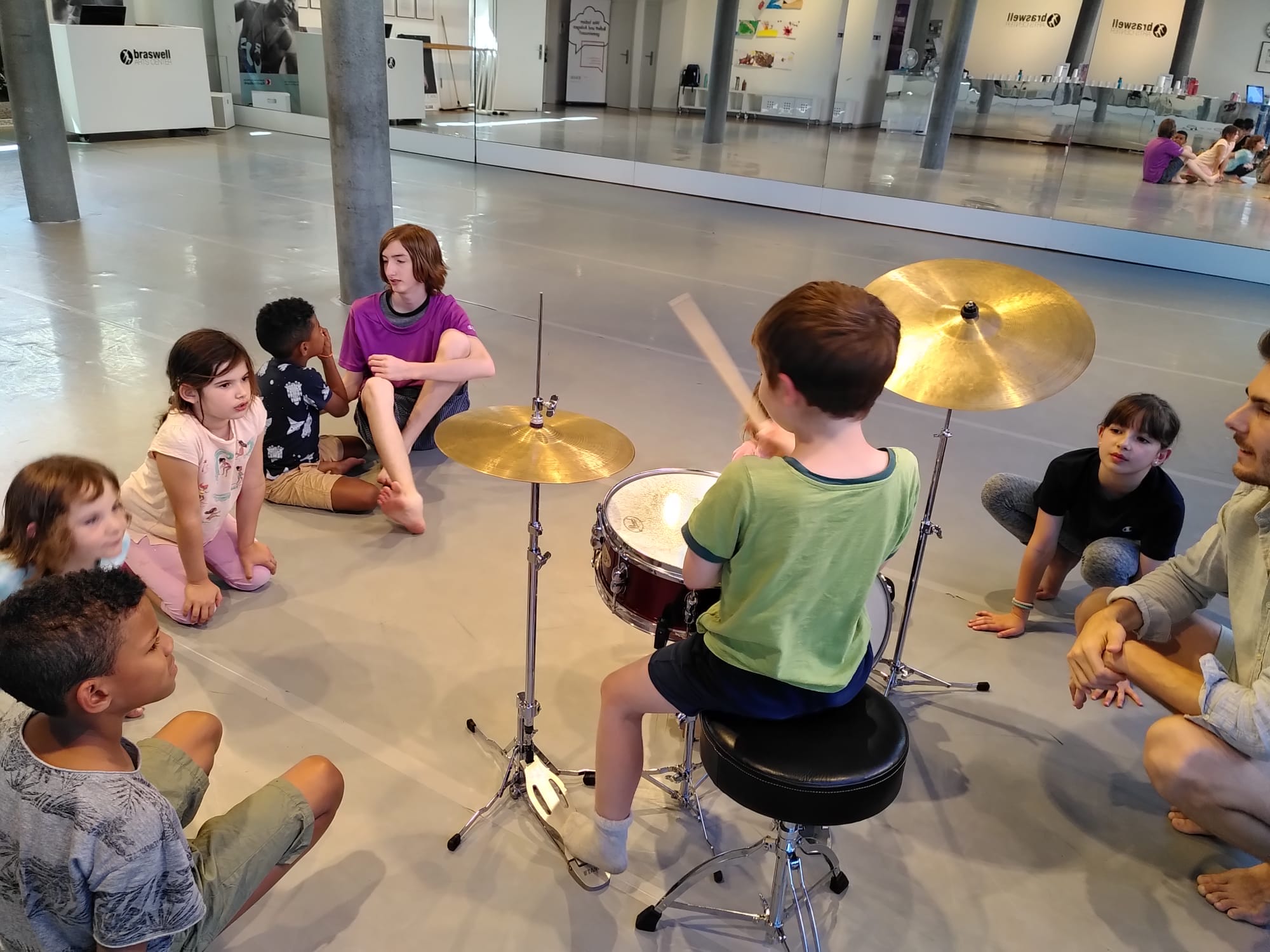 A camper playing drums in a music circle