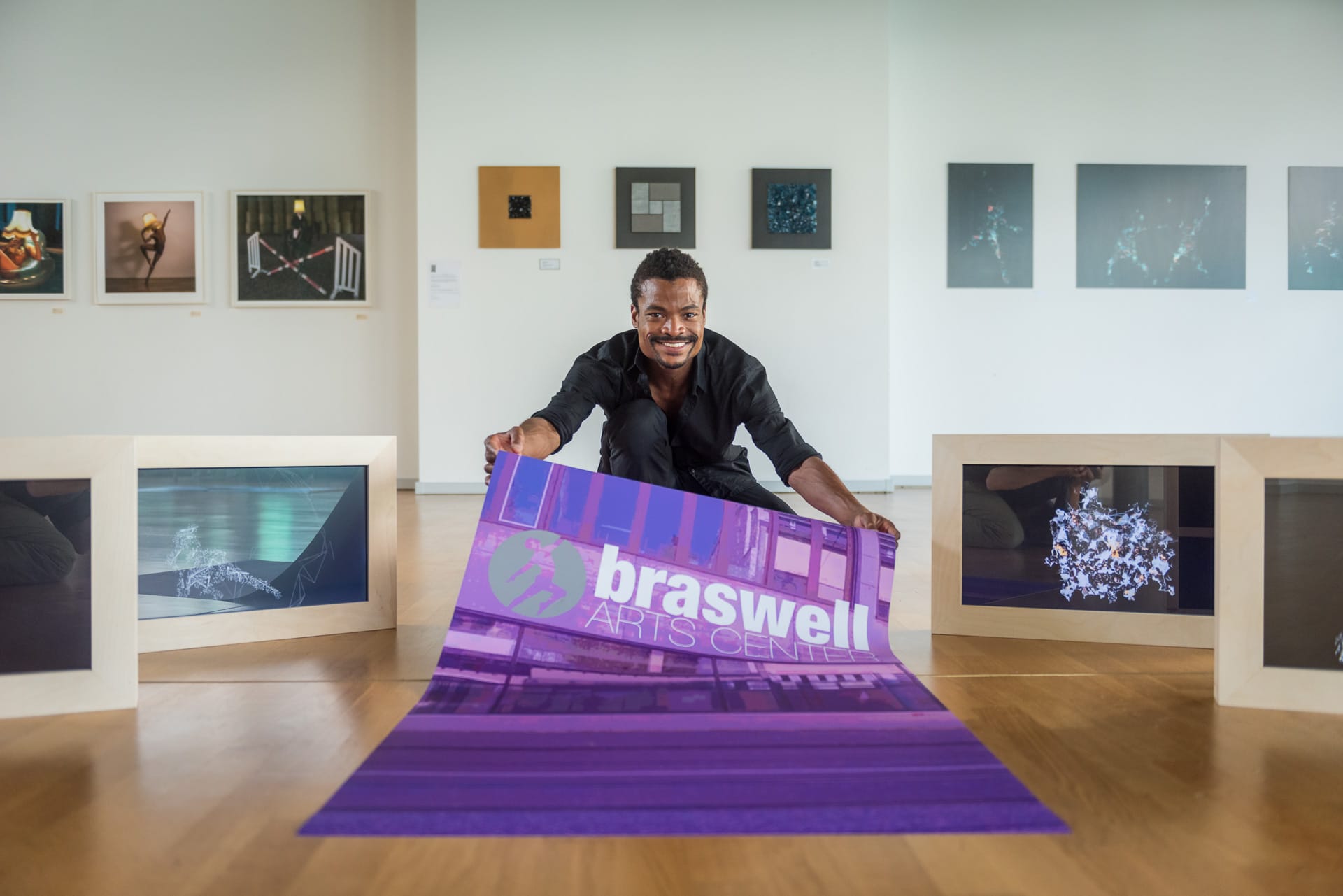 Armando unrolling a Braswell Arts Center poster in the original studio
